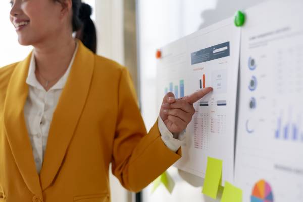 Як франчайзери заробляють: ключі успіху 8 Businesswoman presenting data on a whiteboard in an office setting.