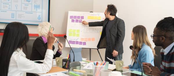 Як франчайзери заробляють: ключі успіху 10 Diverse business team planning project timeline with sticky notes while leader presents strategy